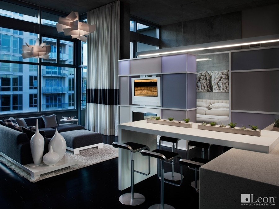 a living room with gray sofas and floor-standing speakers next to a console
